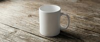 White ceramic coffee mug on rustic wooden table surface for mockup design and branding projects in kitchen or cafe setting.