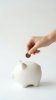 Hand inserting coin into white ceramic piggy bank on neutral background for savings and financial planning concepts.