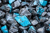 Raw turquoise and black stones in natural formation create striking contrast, with bright blue minerals scattered among dark rough crystals. Macro photography shows mineral texture.