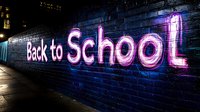 Neon sign displaying Back to School text on brick wall at night with colorful lighting for education marketing campaigns and student promotions.