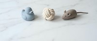 Three handmade clay pet toys on marble surface including blue duck, rope ball and brown mouse for cats and dogs in minimalist style.