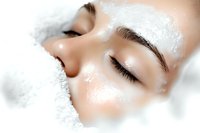 Close up of young Asian woman's face wrapped in soft white towel during spa treatment, eyes closed, showing clean glowing skin and natural eyebrows.