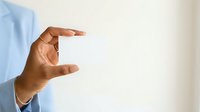 Hand holding blank white card or business card in front of white background, suitable for branding, marketing, and corporate presentations.