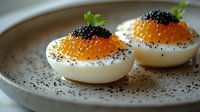 Gourmet deviled eggs topped with red and black caviar, garnished with fresh herbs on ceramic plate with pepper seasoning.