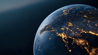 Planet Earth view from space showing illuminated city lights across Europe and North Africa at night, glowing golden against dark blue atmosphere.
