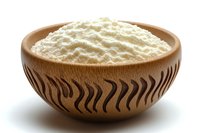 Finely ground white flour in decorative wooden bowl with carved wavy pattern, isolated on white background for food photography and culinary concepts.