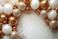 Festive arch made of white, gold and champagne colored balloons with glitter scattered around on light background, creating elegant party decoration.