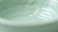 Closeup of pale green liquid surface with ripples and swirling patterns, suitable for cosmetics, skincare, wellness, and beauty product backgrounds.