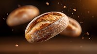Fresh artisan sourdough bread loaves floating with flour particles against warm brown background for bakery marketing and food advertising campaigns.