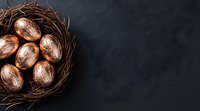 Rose gold metallic Easter eggs arranged in rustic twig nest on dark slate background with copy space, overhead view for seasonal holiday designs.