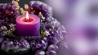 Purple candle burning surrounded by amethyst crystals and dried flowers creating peaceful meditation and wellness atmosphere for spa relaxation.