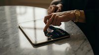 Professional businessman using tablet computer at modern office desk with warm lighting for digital business communication and productivity.