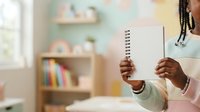 Child with dark skin tone holding spiral notebook in classroom environment with wooden shelves and colorful books, suitable for education, learning, and back-to-school content.