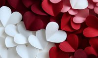 Red and white paper hearts scattered creating romantic background pattern. Delicate textured surface with layered heart shapes in contrasting colors for valentines designs.