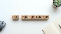 Be prepared for emergencies with this motivational wooden block arrangement on a clean workspace, featuring a succulent plant, mouse, and notebook for readiness planning.