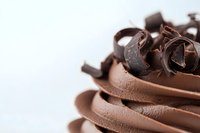 Chocolate curls and shavings arranged in decorative swirls on white background for dessert garnish and culinary presentation.