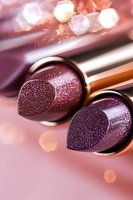 Luxurious burgundy lipsticks with glitter sparkle effect on pink background with bokeh lights, macro cosmetic photography for beauty and makeup advertising.