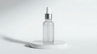 Transparent glass dropper bottle with silver metallic cap on white marble podium, isolated on neutral background, ready for cosmetic, skincare, and pharmaceutical product mockups.