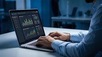Professional businessman analyzing financial data and charts on laptop computer in modern office environment for business analytics and reporting.