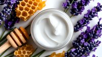 Fresh lavender sprigs with honeycomb, honey dipper and white cosmetic cream in jar on white background, natural skincare and aromatherapy concept.