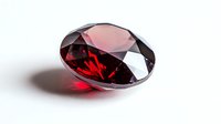 Deep red oval cut gemstone with brilliant facets casting dramatic shadows and reflections on white background, suitable for jewelry design and luxury marketing.
