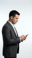 Middle-aged male professional of Caucasian ethnicity wearing charcoal business suit and black tie, holding smartphone while looking at screen. Isolated on white background for corporate and business use.