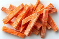 Fresh raw carrot sticks cut into long strips on white background, healthy vegetable snack for diet and nutrition, isolated food photography.
