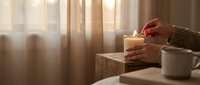 Cozy morning scene with hands holding warm coffee mug by sunny window, soft natural lighting creates peaceful atmosphere for relaxation and comfort.
