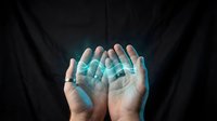 Cupped hands releasing glowing turquoise digital particles against dark background, representing data flow, technology transfer, and innovation concepts for business presentations.