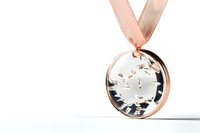 Round rose gold medal with crystal snowflake design hanging from pink ribbon on white background, elegant award symbol isolated for design projects.