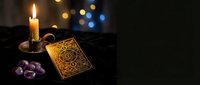 Mystical tarot card reading setup with ornate deck, purple crystals and flickering candle creating atmospheric fortune telling scene for spiritual guidance.