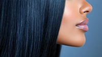 Side profile of young African American woman with straight black hair and glossy lips against blue background, showcasing natural beauty and modern hairstyling.