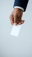 Businessman with dark skin tone holding blank white business card, wearing navy suit jacket with white shirt cuff. Suitable for corporate, professional, and networking concepts.