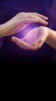 Two hands cupping glowing purple energy orb against dark background. Female hands with silver ring holding magical light for spirituality, healing, wellness, and alternative medicine concepts.