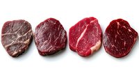 Four raw beef steaks with rich marbling arranged in a row on white background, isolated for culinary, restaurant menu, and food blog use.