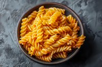 Rotini pasta with rich orange cheese sauce served in rustic brown ceramic bowl on dark textured background, appetizing comfort food photography.