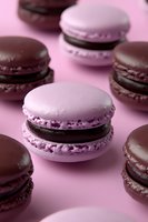 French macarons in pink and chocolate colors arranged on pink background, close-up view showing delicate meringue texture and ganache filling for pastry shop menu.