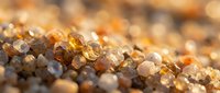 Close-up of golden and translucent sand grains with warm sunlight creating sparkle and texture, suitable for beach, nature, and travel backgrounds.