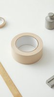 Beige masking tape roll with office supplies on white background for packaging and crafting projects.