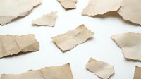 Torn brown paper pieces scattered on white background creating vintage texture pattern for craft projects and design elements.