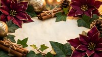 Festive Christmas frame with burgundy poinsettia flowers, cinnamon sticks, golden ornaments and green leaves on wooden background for holiday greeting cards.