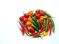 Assorted fresh chili peppers and bell peppers isolated on white background, including red, green, yellow and orange varieties for culinary and food design use.