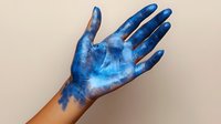 Hand covered in blue paint with artistic brush strokes and texture, isolated on neutral background for creative design projects and art concepts.