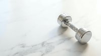 Single chrome dumbbell weight on marble surface for fitness, gym training, strength exercise, and workout routines.