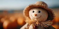 Cheerful autumn scarecrow decoration with smiling face and straw hat against warm bokeh background for seasonal harvest celebrations and fall decor projects.