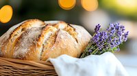 Fresh crusty artisan bread loaf in rustic basket with lavender flowers, white linen napkin against soft bokeh background, food photography styling.