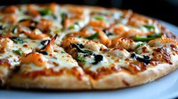 Homemade seafood pizza with grilled shrimp, melted mozzarella cheese, fresh herbs, and tomato sauce on crispy thin crust, close-up view on white plate.