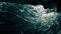 Dynamic ocean wave with crystalline water droplets and foam crashing in dramatic motion against dark background for marine and nature concepts.