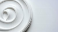White creamy swirl texture with smooth flowing curves on light background for skincare cosmetics and dairy product packaging design applications.