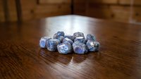 Raw sodalite gemstones scattered on wooden surface showing natural blue mineral crystals for jewelry making and crystal healing practices.